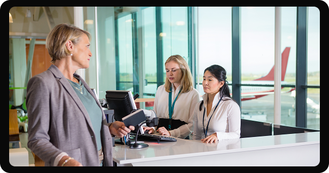 People checking in at airport counter with staff assisting