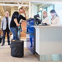 People at airport counter checking in with luggage